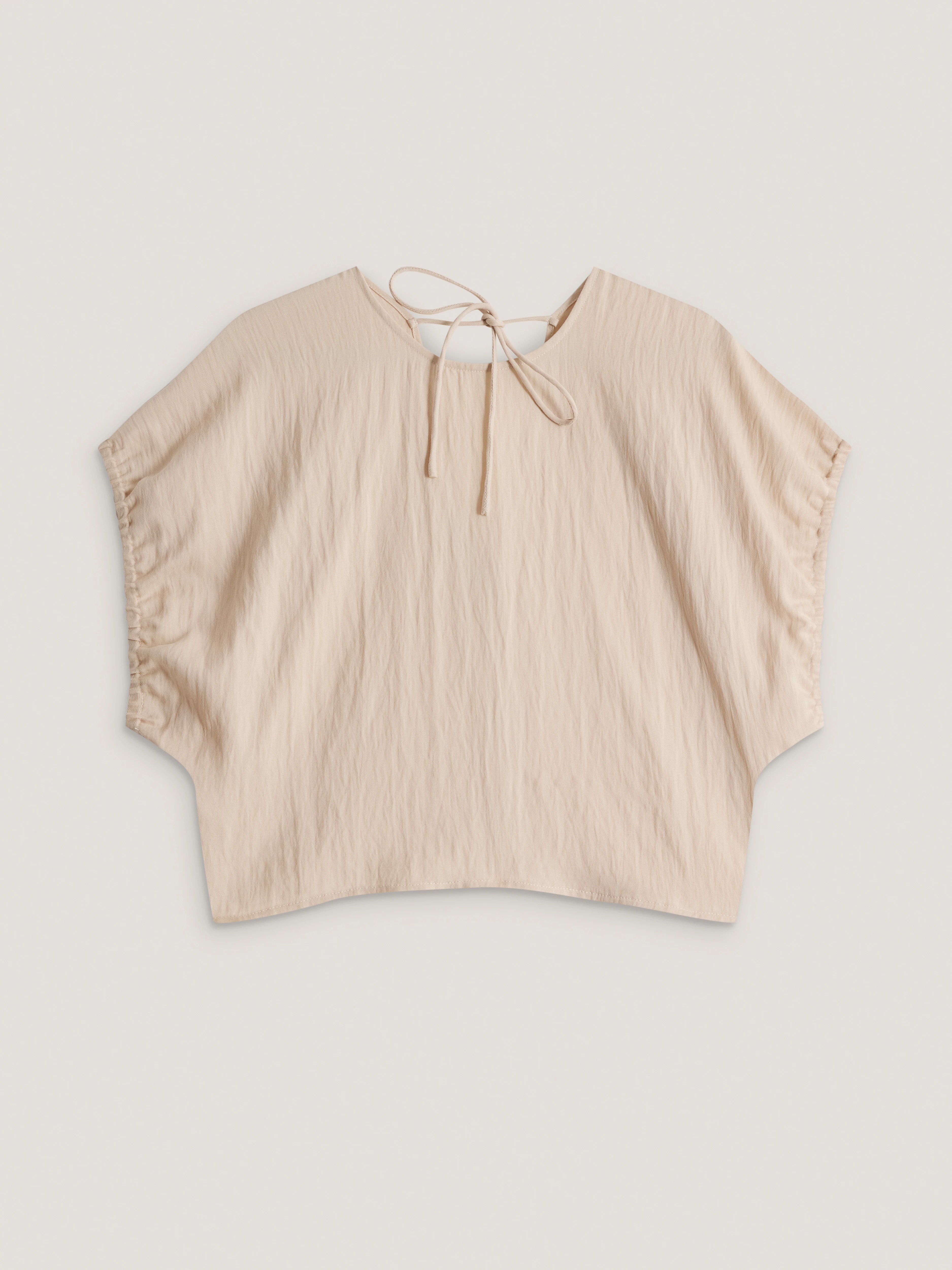 A light beige blouse with a cut-out at the back