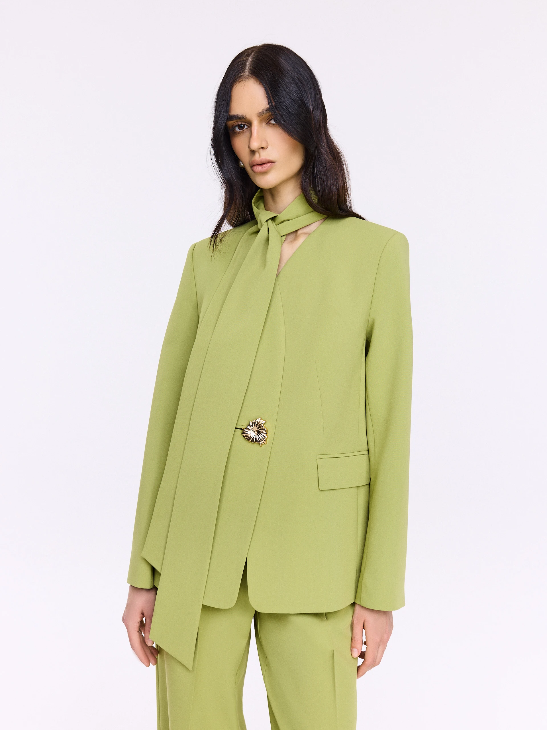 Green jacket with a sash and a jeweled button