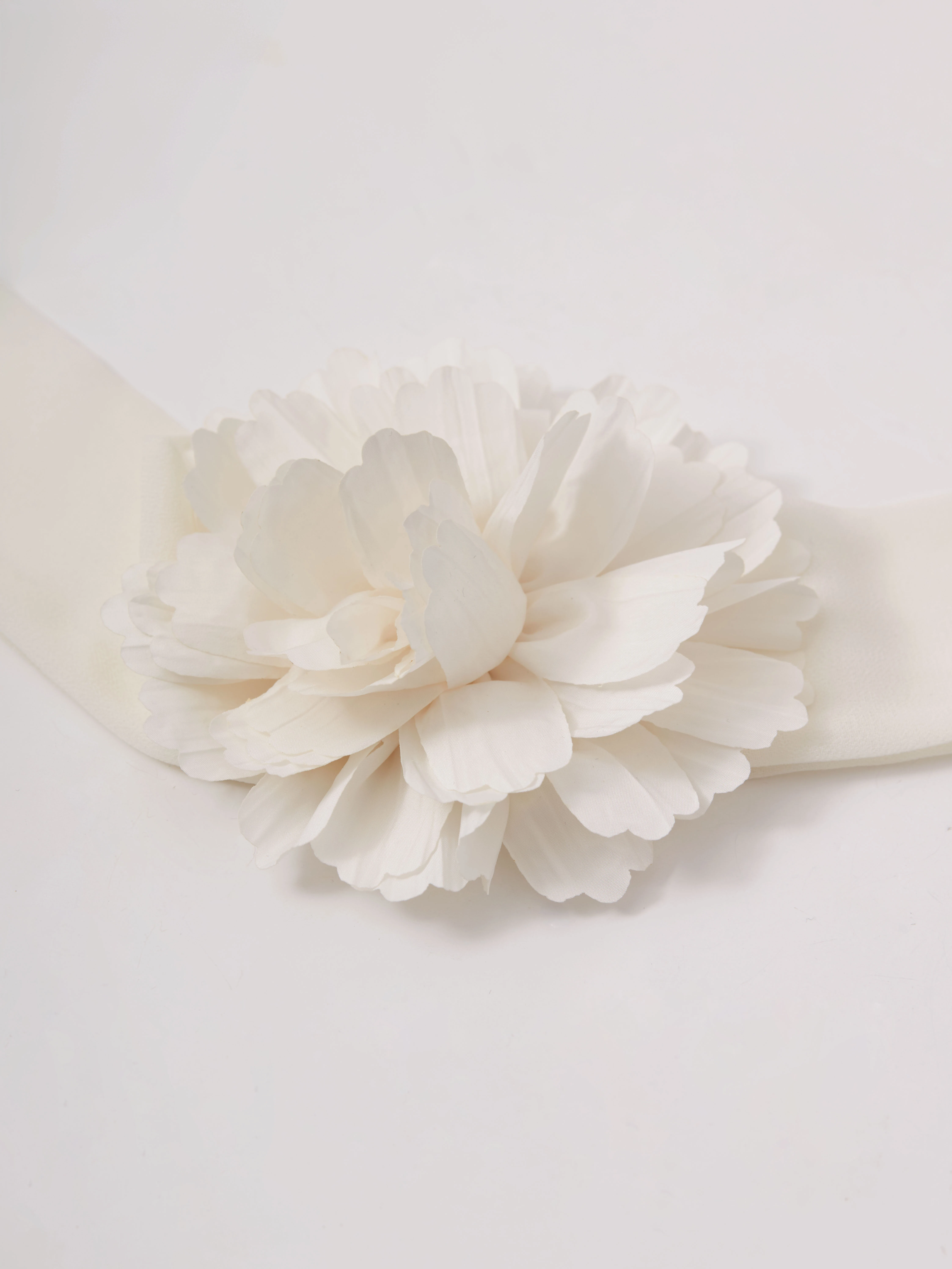A cream-colored scarf-style necklace with a flower