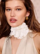 A cream-colored scarf-style necklace with a flower