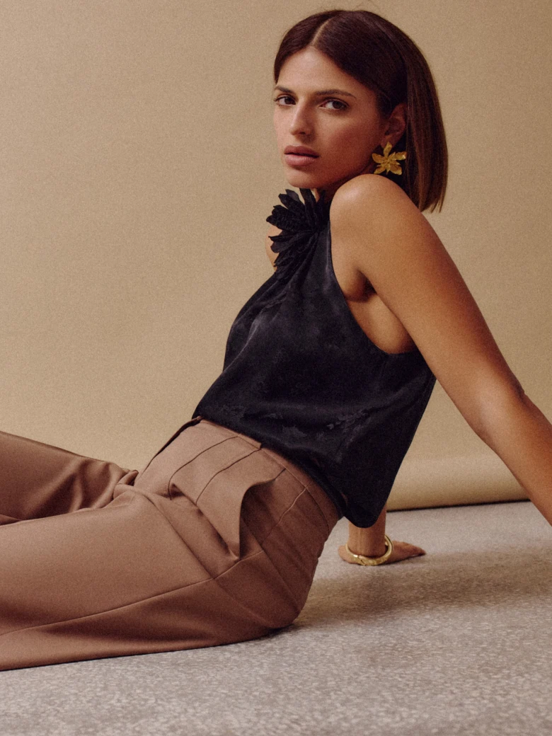 Black blouse with halter neckline and flower at the neck