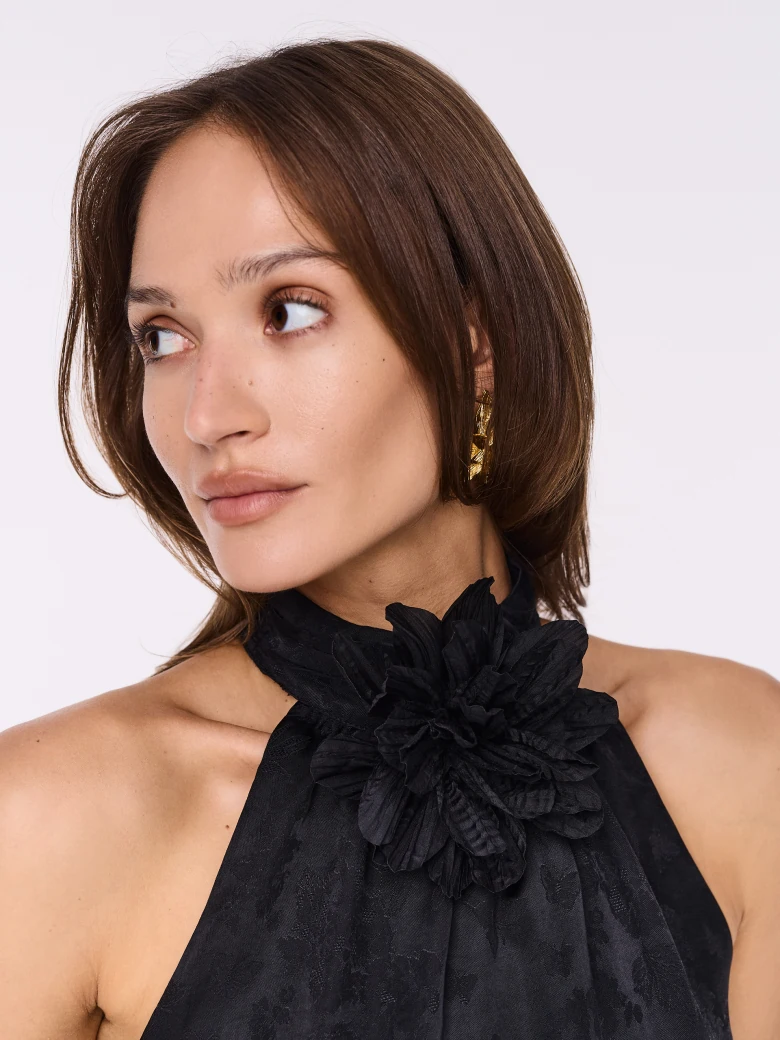 Black blouse with halter neckline and flower at the neck