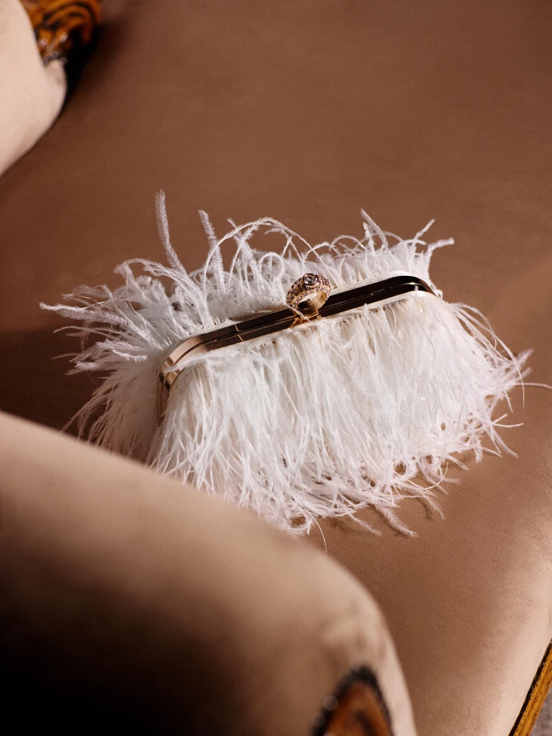A small cream-colored handbag embroidered with feathers
