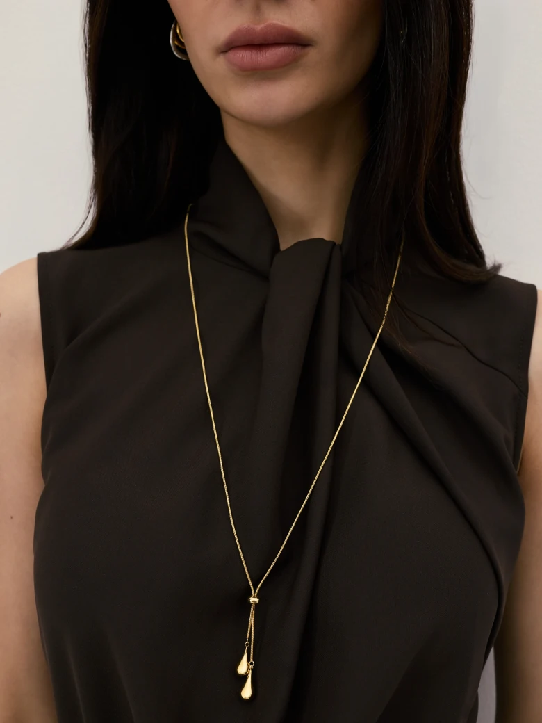A long, gold-plated necklace with a bow